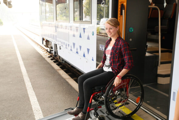 Rollstuhlfahrerin bei Ausstieg über angelegte Rampe am Fahrzeug