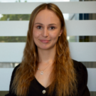 Mitarbeiterporträt der Recruiterin in moderner Büroumgebung vor Glaswand mit Milchglasstreifen