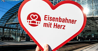 Logo auf Herz wird vor Bahnhof gehalten